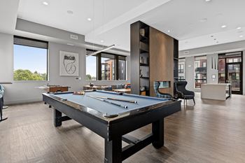 A pool table is in the middle of a room with a wood floor.